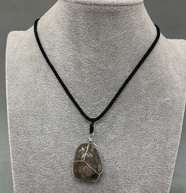 Pendant in a silver-plated weave with natural Jasper, dimensions approximately 35×20 mm +/- on a cord, cord diameter 2.5 mm +/-, length 50 cm +/-