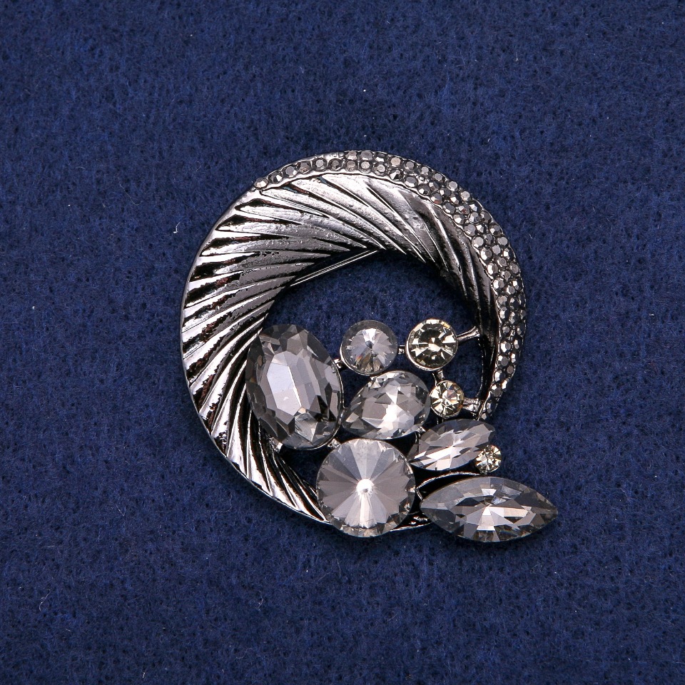 Брошка кругла Ободок з стразами, сплітаються в красиву композицію, темний метал 45х50мм